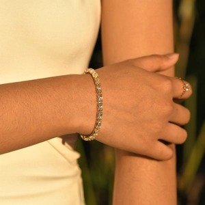 Elegant gold bracelet with rectangular zircon stones worn by a model in natural light