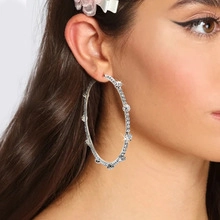 Close-up of large silver hoop earrings with white rhinestones on a female model