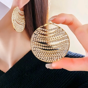 Gros plan de boucles d'oreilles créoles dorées avec strass brillants sur l'oreille