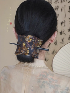 Detail of embroidered floral fabric hair bun cover with a golden butterfly metal accessory