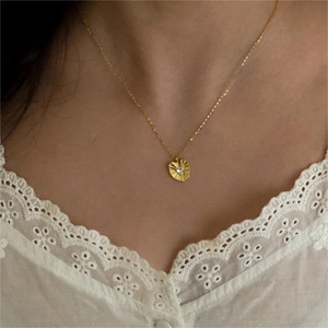 Close-up of heart pendant necklace with sunburst texture and white zircon on a model
