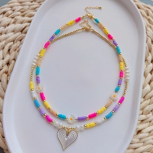 Detail of bohemian daisy beaded necklaces with colorful clay beads and heart pendant