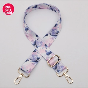 Close-up of pink and blue tie-dye bag strap with adjustable gold-toned metal hardware
