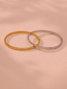 Detail of gold and silver stainless steel bangles with textured segmented design and shadows