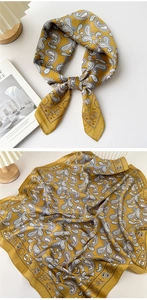 Detail of yellow silk scarf featuring paisley patterns and elegant knotted styling