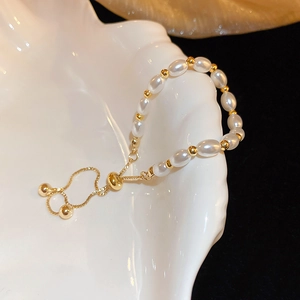 Elegant adjustable pearl bracelet with gold beads on a decorative white shell
