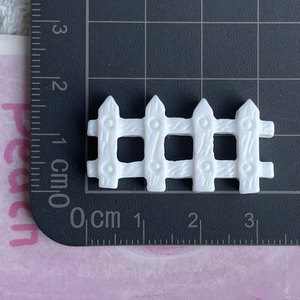 Macro shot of white miniature resin fence on scale mat showing dimensions for DIY crafts
