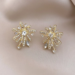 Macro shot of 18k gold fireworks earrings with pearls and crystals on champagne silk