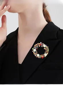 Dettaglio di una spilla ghirlanda vintage con strass colorati su un blazer nero elegante