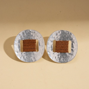 Detail shot of silver hammered metal earrings with brown textured leather inlay