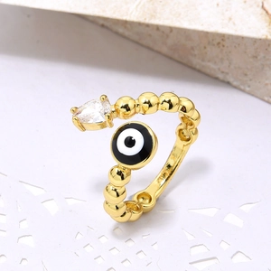 Detail of gold evil eye ring with blue zircon drop on white lace and stone background