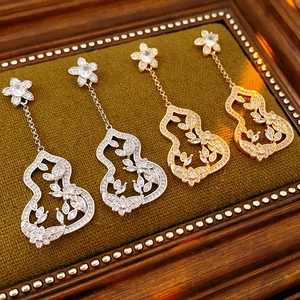 Détail de boucles d'oreilles fleurs argentées et dorées avec zircons sur plateau velours