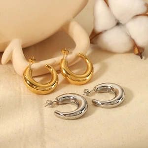 Polished 18K gold and silver chunky C-shaped hoop earrings on elegant beige background