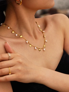 Detail view of gold shell necklace with freshwater pearls worn by a model