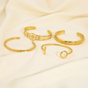 Detailed close-up of four-piece gold stainless steel bangles set on beige satin fabric