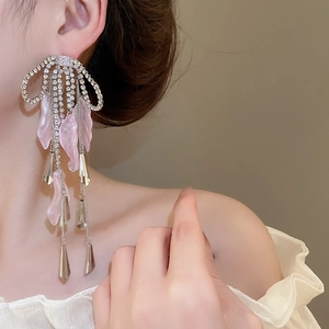 Detailed close-up of pink petal bow earrings with long sparkling rhinestone tassels