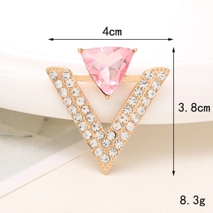 Detailed view of a V-shaped gold brooch with a large pink triangle rhinestone and small crystals