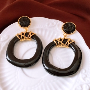 Close-up of vintage resin hollow earrings with gold accents on a ceramic plate