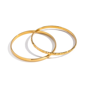 Dettaglio del set di due bracciali in acciaio dorato con texture lisce e martellate