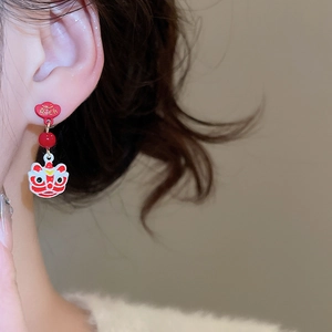 Close-up of a model wearing a red lion dance earring with a RICH heart stud