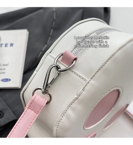 Detail of silver metallic hardware and pink leather trim on the ghost-themed round bag