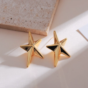 Minimalist gold star stud earrings with a polished mirror finish on a stone background