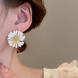 Close-up of model wearing white daisy raffia stud earrings for a boho vacation look