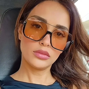 Close-up of stylish double bridge sunglasses with orange lenses on a female model