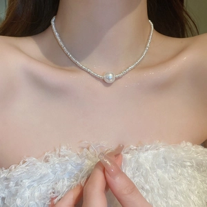 Close-up of a silver bow pearl necklace on collarbone showing elegant texture