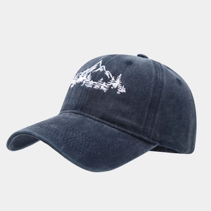 Close-up of embroidered mountain forest scenery on a washed navy cotton baseball cap