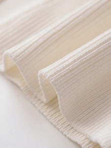 Close-up detail of soft creamy white ribbed knit fabric texture and fine weaving