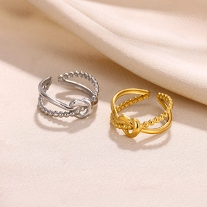 Detail of twisted and beaded open rings in gold and silver finish on silk fabric