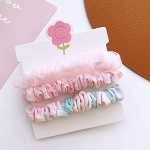 Gros plan de trois chouchous en tissu floral rose sur une carte de présentation