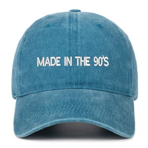 Close-up of 'MADE IN THE 90'S' white embroidery on washed blue cotton baseball cap