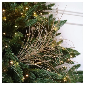 Close-up of golden glitter sprays on a Christmas tree with warm white lights