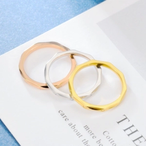 Three geometric faceted titanium steel rings in rose gold, silver, and gold finishes