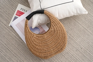 Detail of handmade straw crossbody bag with black leather handle on casual vacation background