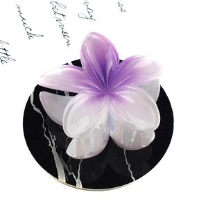Macro shot of purple gradient frangipani flower hair claw clip on marble display