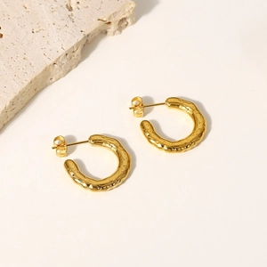 Detailed macro view of 18K gold stainless steel C-shape earrings with lava texture design