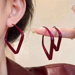 Deep red geometric earrings with irregular quadrangle design shown on model and hand