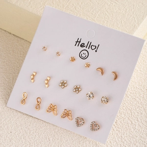 Collection of nine pairs of gold-plated stud earrings featuring stars, moons, and pearls