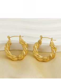 Detailed macro view of 18k gold twisted rope hoop earrings on luxury silk fabric