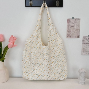 Floral embroidered canvas tote bag hanging on wall with decorative tulips and artsy decor