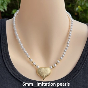 Detail of 6mm imitation pearl necklace featuring an 18K gold plated heart pendant