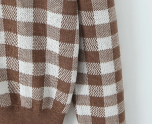Close-up of brown checkerboard knit fabric showing fine texture and ribbed cuffs