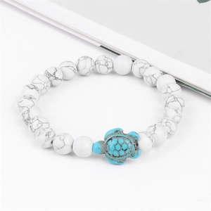 Detail of white marble beads bracelet with a turquoise sea turtle charm pendant