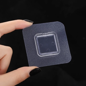 Close-up of a square transparent adhesive hook patch with a flexible PVC snap base