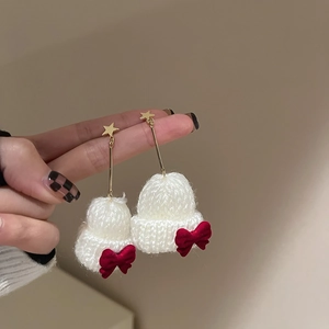 Detailed shot of handmade mini knitted hat earrings with velvet bows and star studs