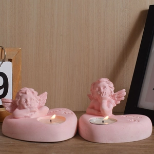 Detail of pink heart-shaped candle holders with angel relief and lit tealight candles