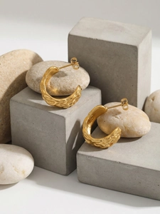 Detail of 18k gold plated C-shape earrings with hammered texture on stone pedestals